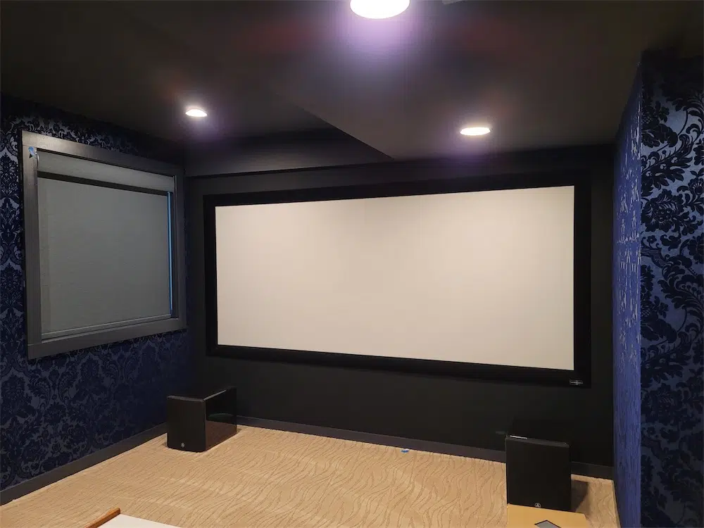 Finished media room with a projection screen, recessed lighting and patterned wall finishes