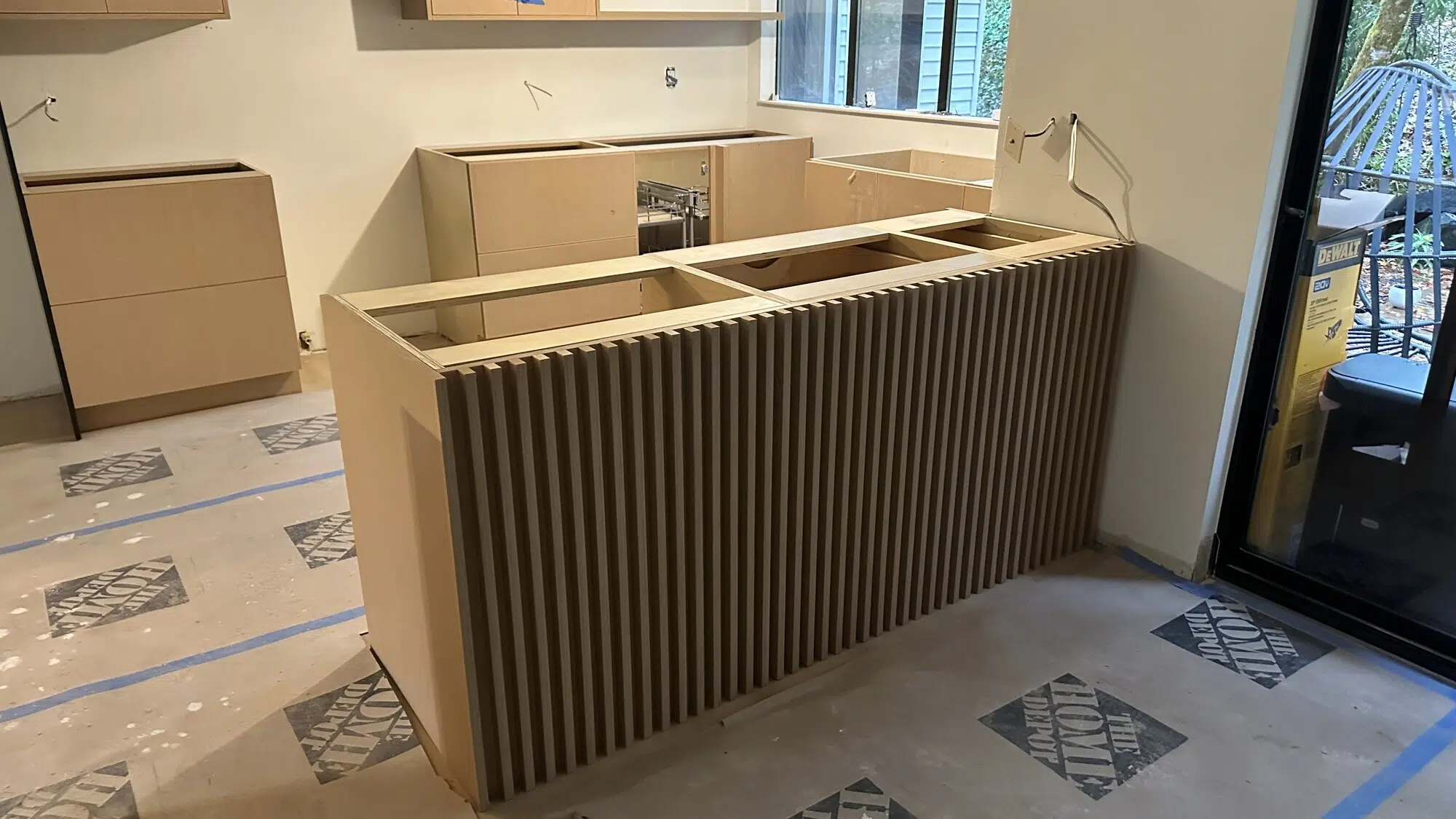 Custom wood-slat kitchen island and cabinet installation in progress