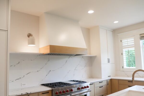 Custom Range Hood and Quartz Backsplash Custom range hood above gas range with quartz backsplash