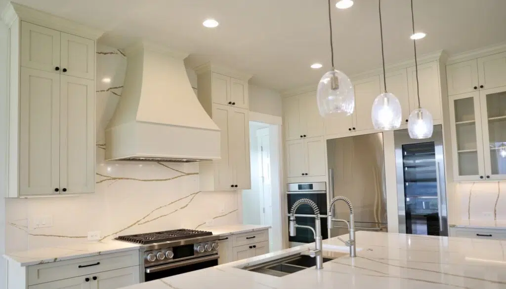 Custom white kitchen cabinets, quartz backsplash, and island