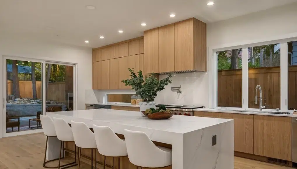 Remodeled kitchen with wood cabinets, a white waterfall island and counter seating